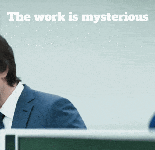 a man in a suit and tie stands in front of a sign that says the work is mysterious
