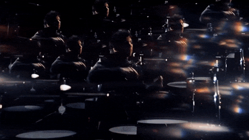 a group of people are playing drums in a dark room .