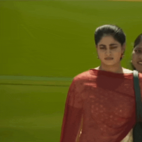 two women are walking in front of a green background .