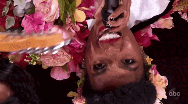 a woman with flowers on her head is singing into a microphone ..