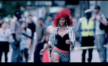a woman with red hair is dancing in a crowded street