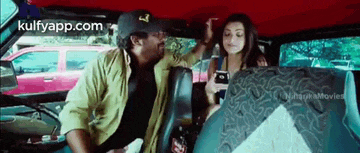 a man and a woman are sitting in the back seat of a car talking to each other .
