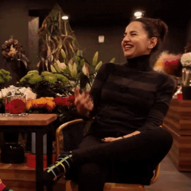 a woman wearing a black turtleneck and colorful socks is sitting in a chair