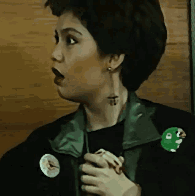 a woman with a tattoo on her neck has a green button on her jacket that says ' a '