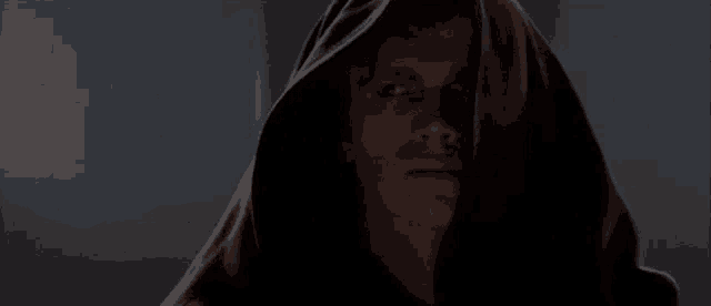 a man wearing a black hooded cloak is looking at the camera .