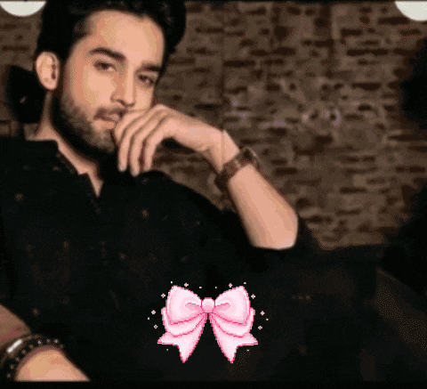 a man with a beard is sitting on a couch with a pink bow in front of him