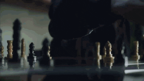 a close up of a chess board with a person standing behind it