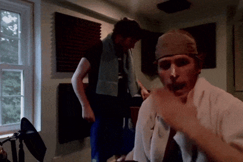 a man with a towel around his neck is talking to another man in a room