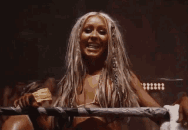 a woman with long hair and braids is standing in a dark room