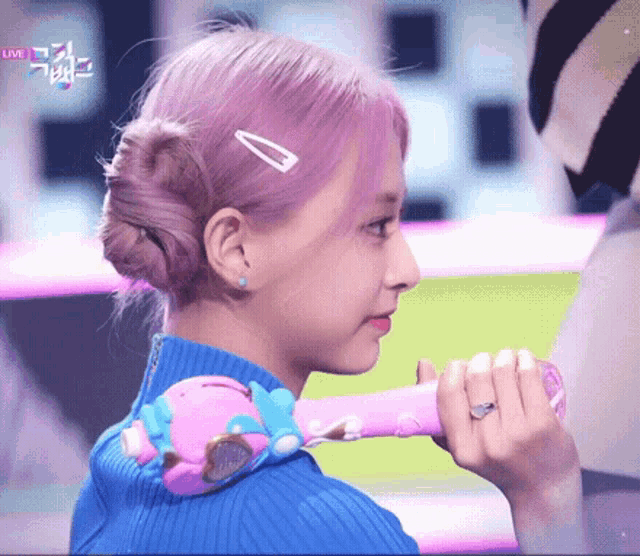 a woman with pink hair is holding a pink object in her hand