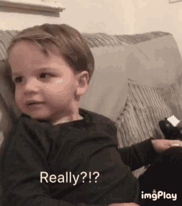 a young boy is sitting on a couch with the words really written below him