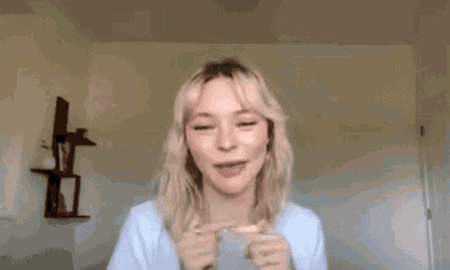 a woman with blonde hair is making a funny face while wearing a white shirt .