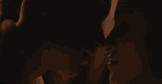 a close up of a man and a woman kissing in the dark .