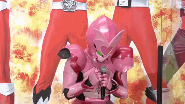 a pink robot is holding a microphone in front of a group of red guys .