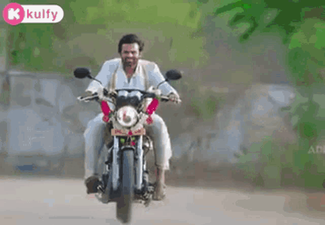a man is riding a motorcycle down a dirt road with trees in the background .