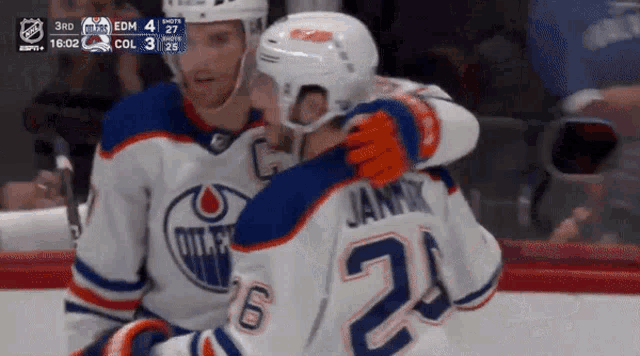 a hockey player with the number 24 on his jersey hugging another player