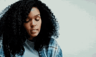 a woman with curly hair and a plaid shirt is looking down .