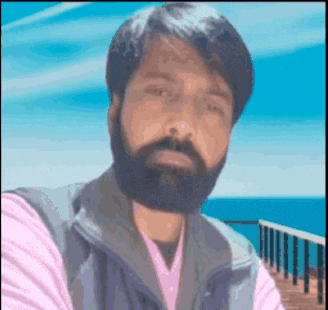 a man with a beard is taking a selfie with the ocean in the background .