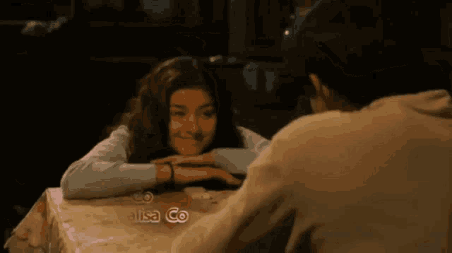 a girl sitting at a table with her head resting on a man 's lap .