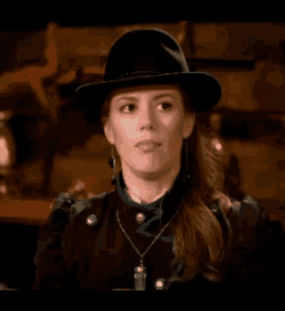 a woman wearing a hat and a necklace is making a face .