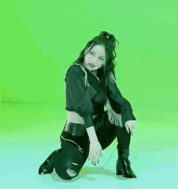 a woman in a black crop top and black pants is kneeling on the floor .
