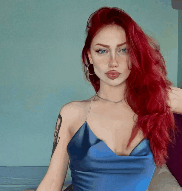 a woman with red hair and a tattoo on her arm