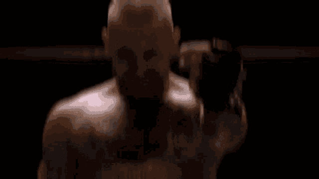 a man with a tattoo on his chest is standing in a dark room holding a boxing glove .