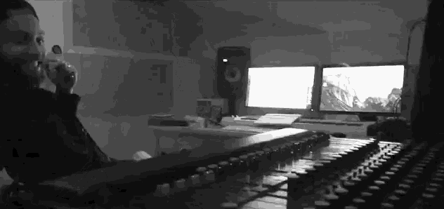 a black and white photo of a man sitting at a desk in front of two computer monitors