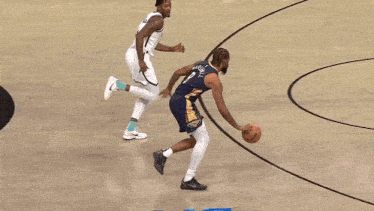 two basketball players on a court with blue written on the floor