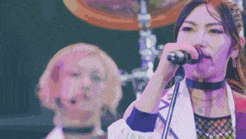 a woman singing into a microphone while another woman looks on