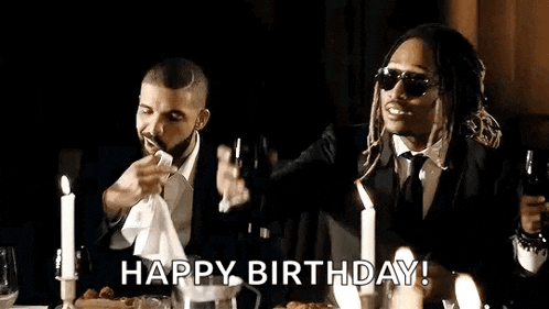 two men in suits are sitting at a table with candles and toasting with champagne .