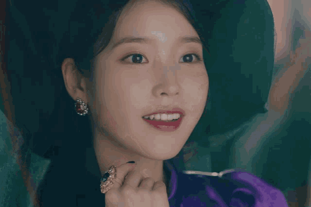 a woman in a purple dress and black hat smiles