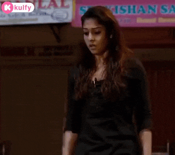a woman in a black dress is standing in front of a sign that says ' srikishan ' on it .