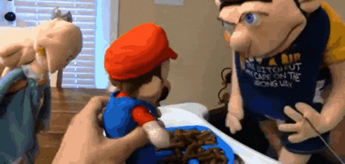 a mario puppet is being held by a person wearing a shirt that says " bitch put your cape on the wrong way "