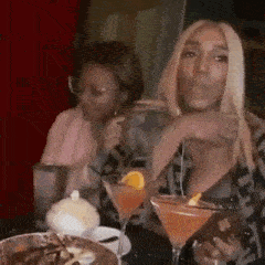 a woman is sitting at a table with a martini glass and a credit card .