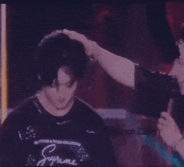 a man in a black shirt with a star on it is holding a microphone while standing on a stage .