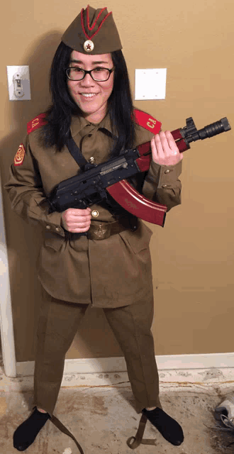 a woman in a military uniform holds a gun with the letter c on it