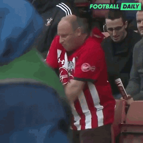 a man in a red and white striped shirt is standing in a stadium with the words football daily on the bottom