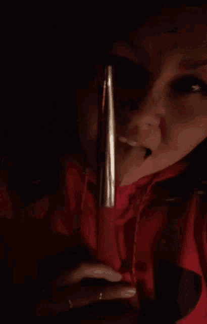 a woman wearing a red nike hoodie is licking a pink lipstick