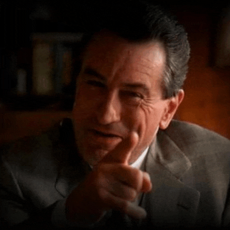 a man in a suit is pointing his finger at the camera .