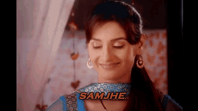 a woman in a blue dress is smiling with the word samjhe in orange