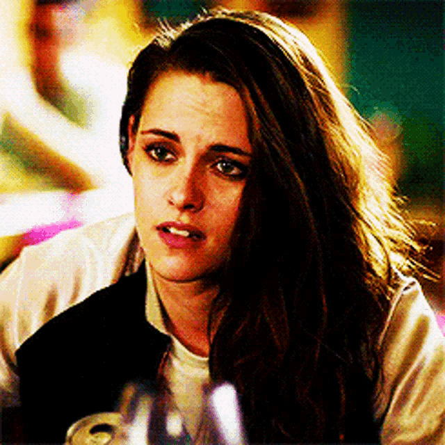 a woman with long brown hair is sitting at a table with a glass of wine .
