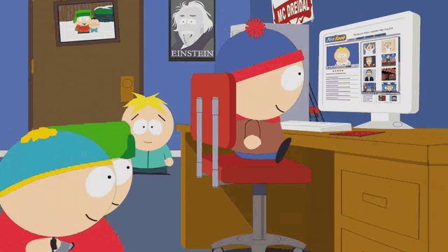 a poster of einstein hangs on a wall above a computer monitor