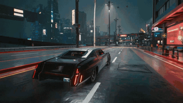 a car is driving down a city street at night and has a license plate that says ' tfs ' on it