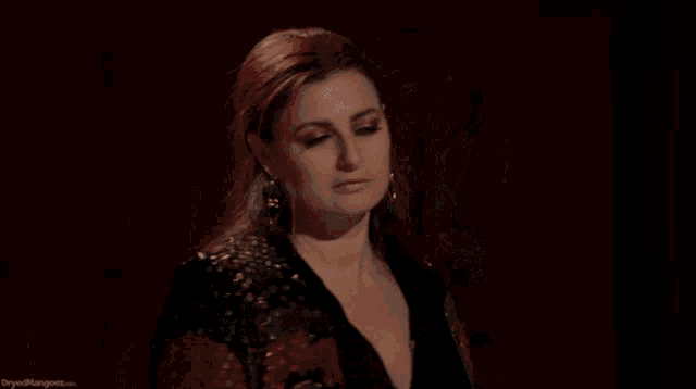 a woman with red hair is wearing earrings and a black jacket