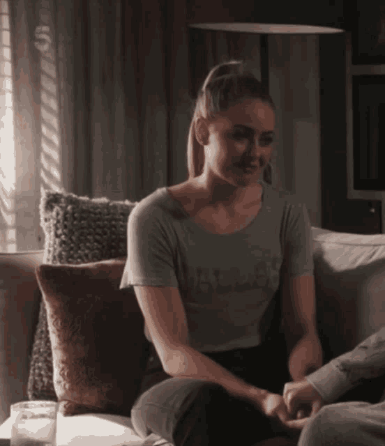 a woman sits on a couch wearing a gray shirt that says dallas