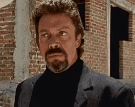 a man with a beard is wearing a suit and a black turtleneck .