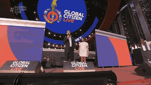 a man and a woman stand on stage at a global citizen live