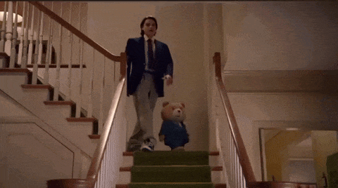 a man in a suit is walking down a set of stairs with a teddy bear