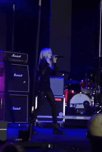 a person standing on a stage with a marshall amplifier in the background